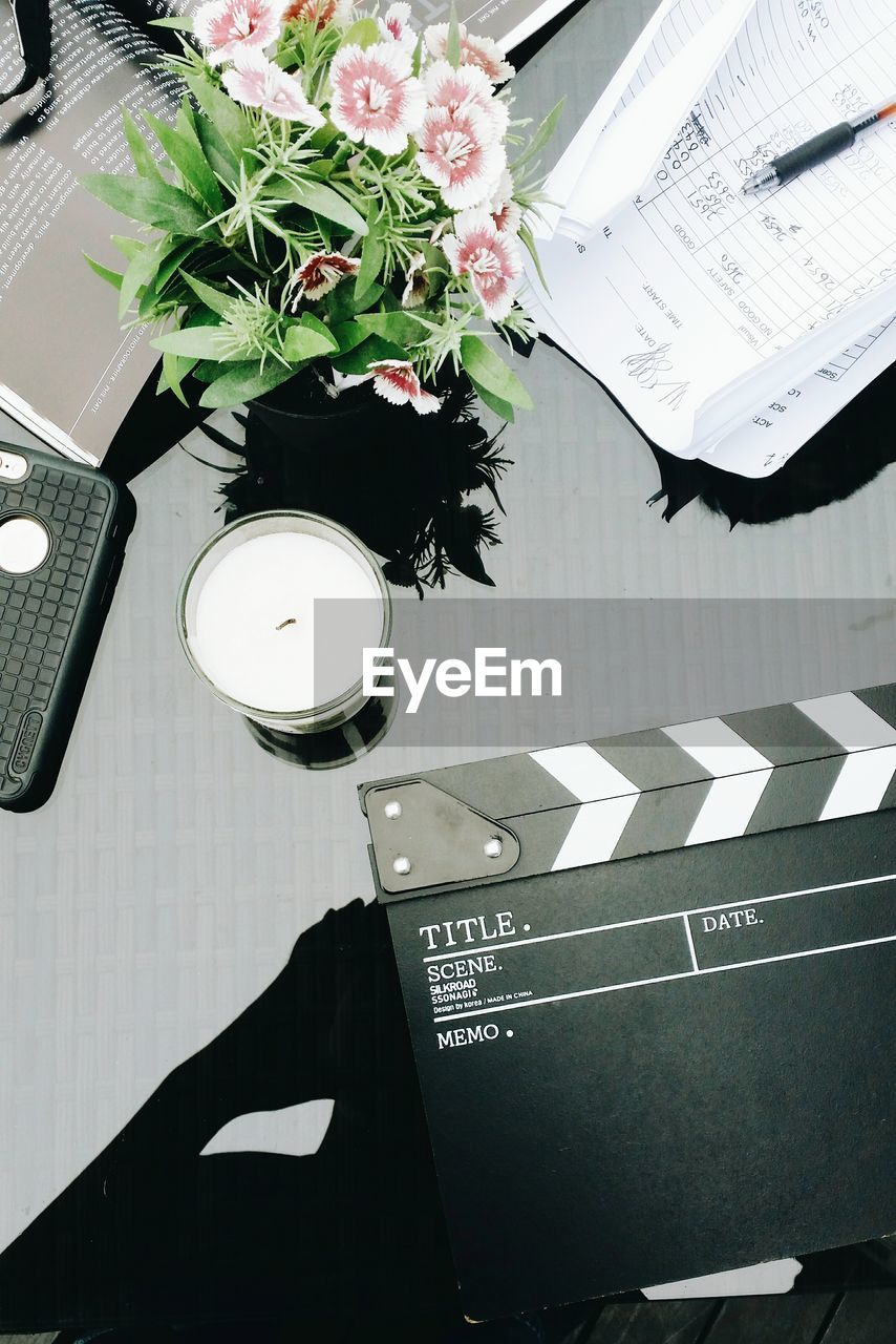 High angle view of tea light with film clapper and flowers on table