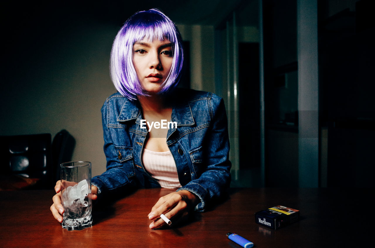 PORTRAIT OF BEAUTIFUL YOUNG WOMAN SITTING ON TABLE