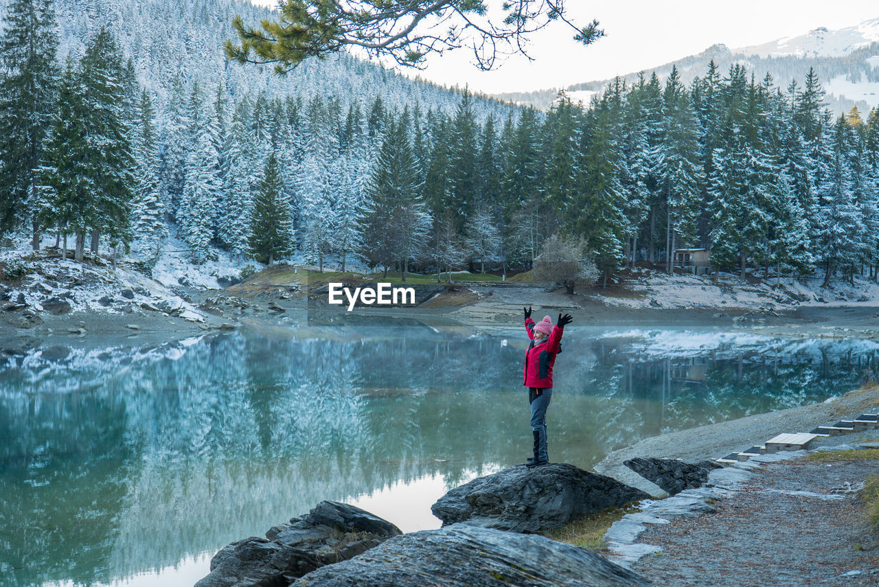 Woman standing on rock by lake during winter