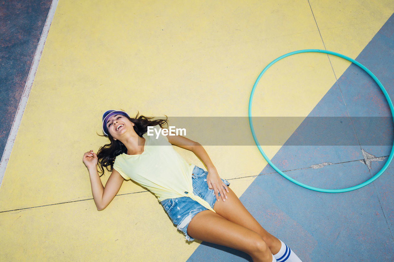 Happy woman lying by hoop on sports court