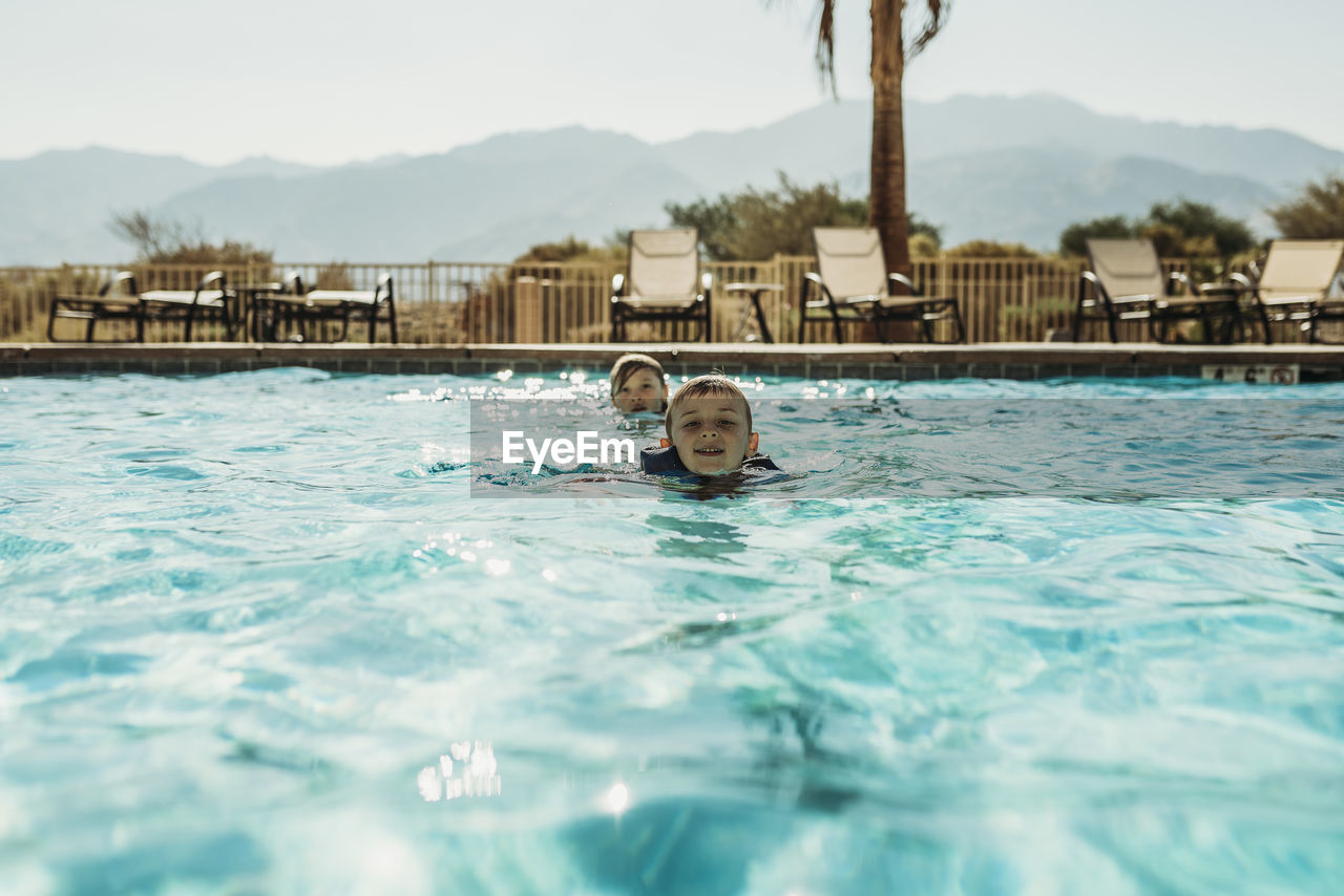 Young brothers swimming in large pool in california on vacation