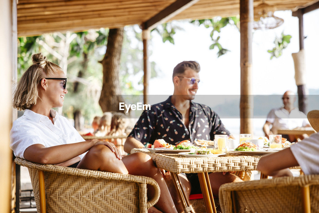 Smiling heterosexual couple sitting at table with breakfast in resort