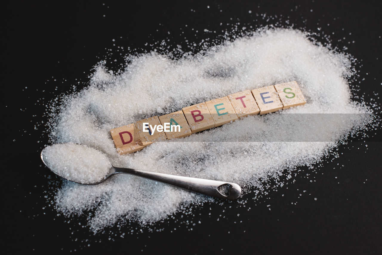 Heap of sugar with handwritten diabetes word on black background. concept of diabetes