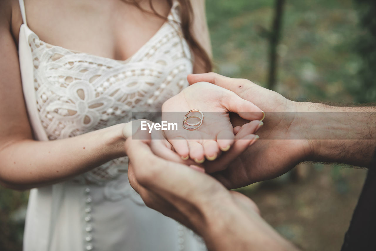 MIDSECTION OF MAN HOLDING WOMAN STANDING AGAINST BLUE