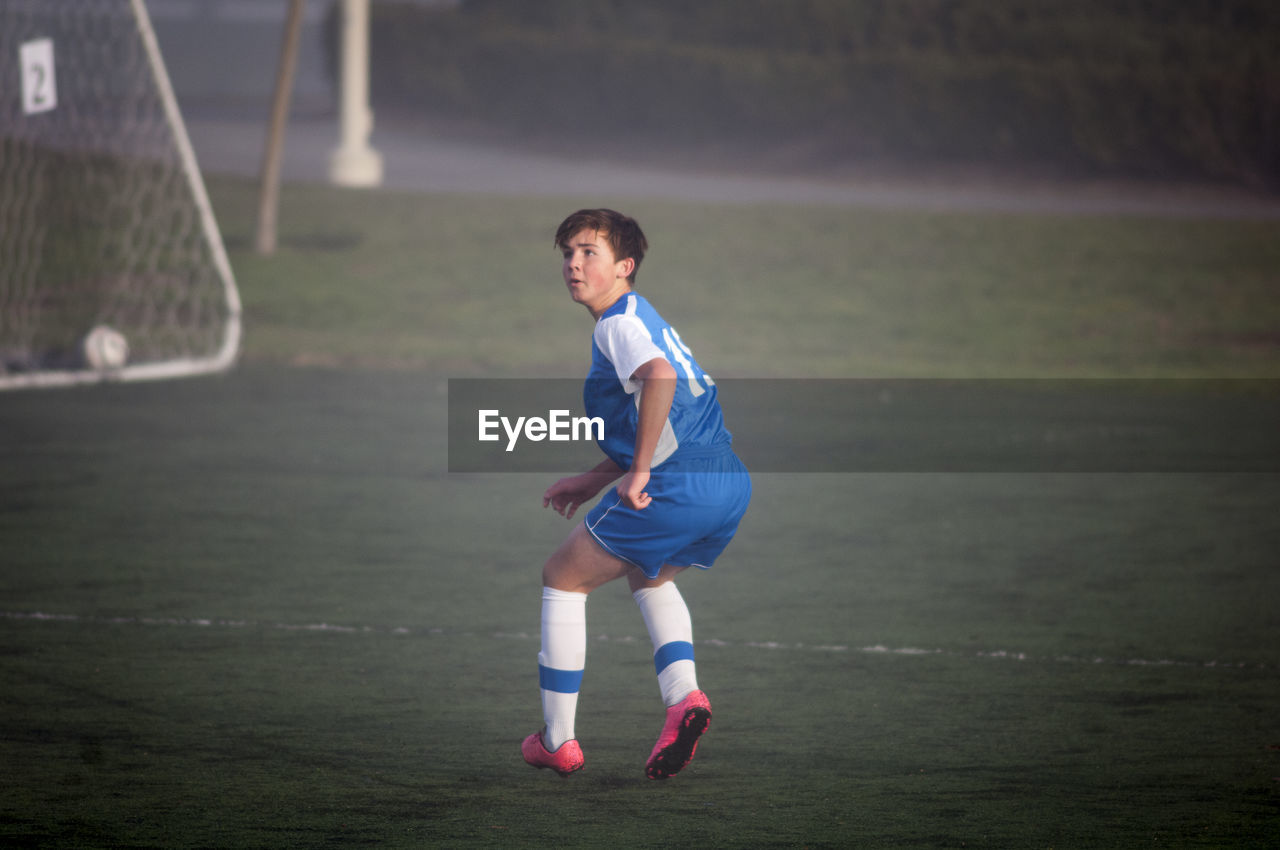 Teen soccer player ready to defend on a foggy field