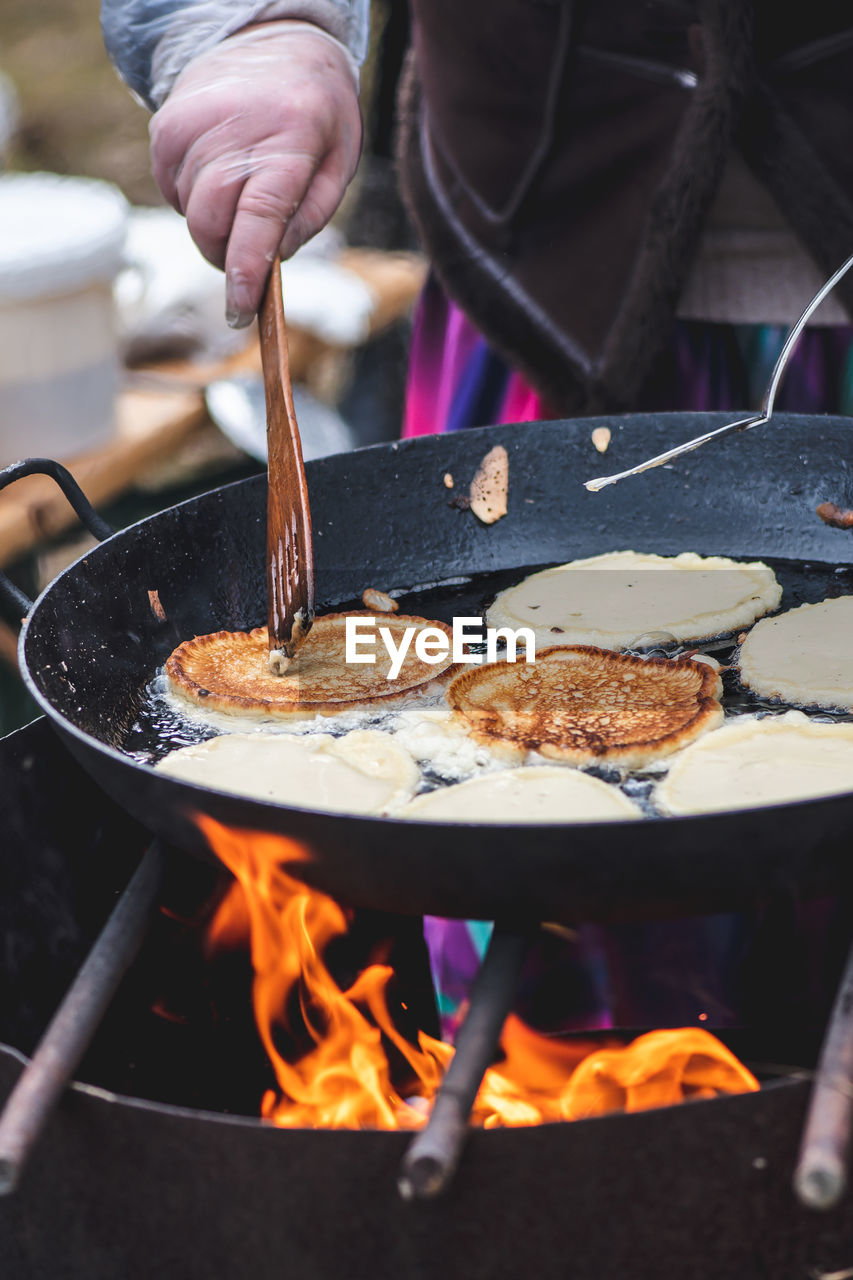 Cooking blini, blin or blynai, pancakes traditional sweet food, preparing outdoor on an open fire