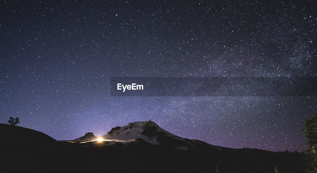 Scenic view of snowcapped mountains against star field at night