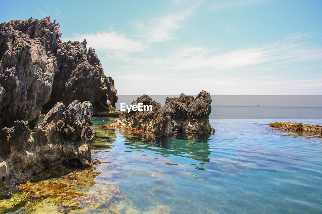 Rocks in sea against sky