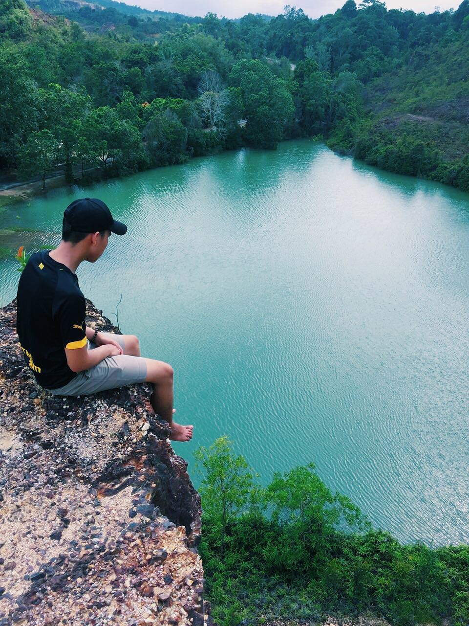 WOMAN SITTING ON ROCK BY LAKE