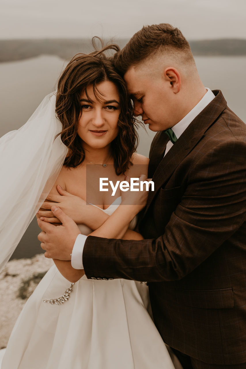 portrait of bride and groom standing against wall