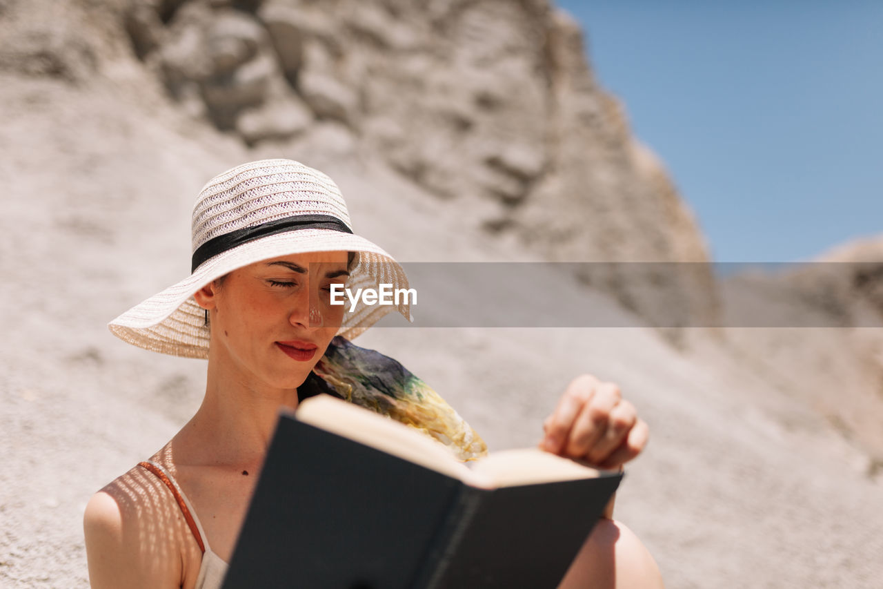 Midsection of woman reading book on beach