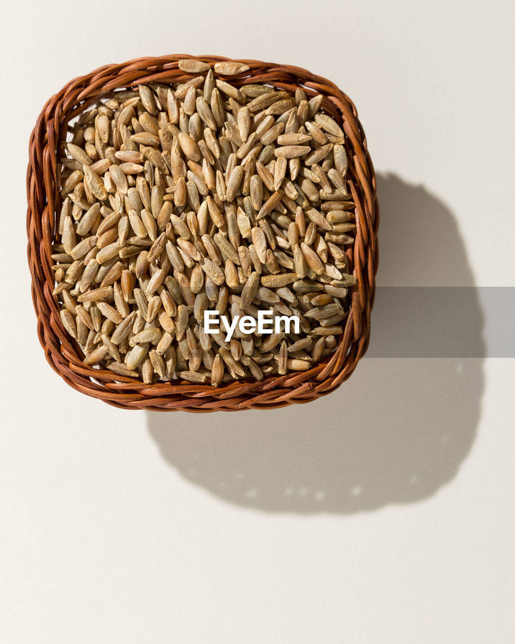 Close-up of wheat grain on basket against white background