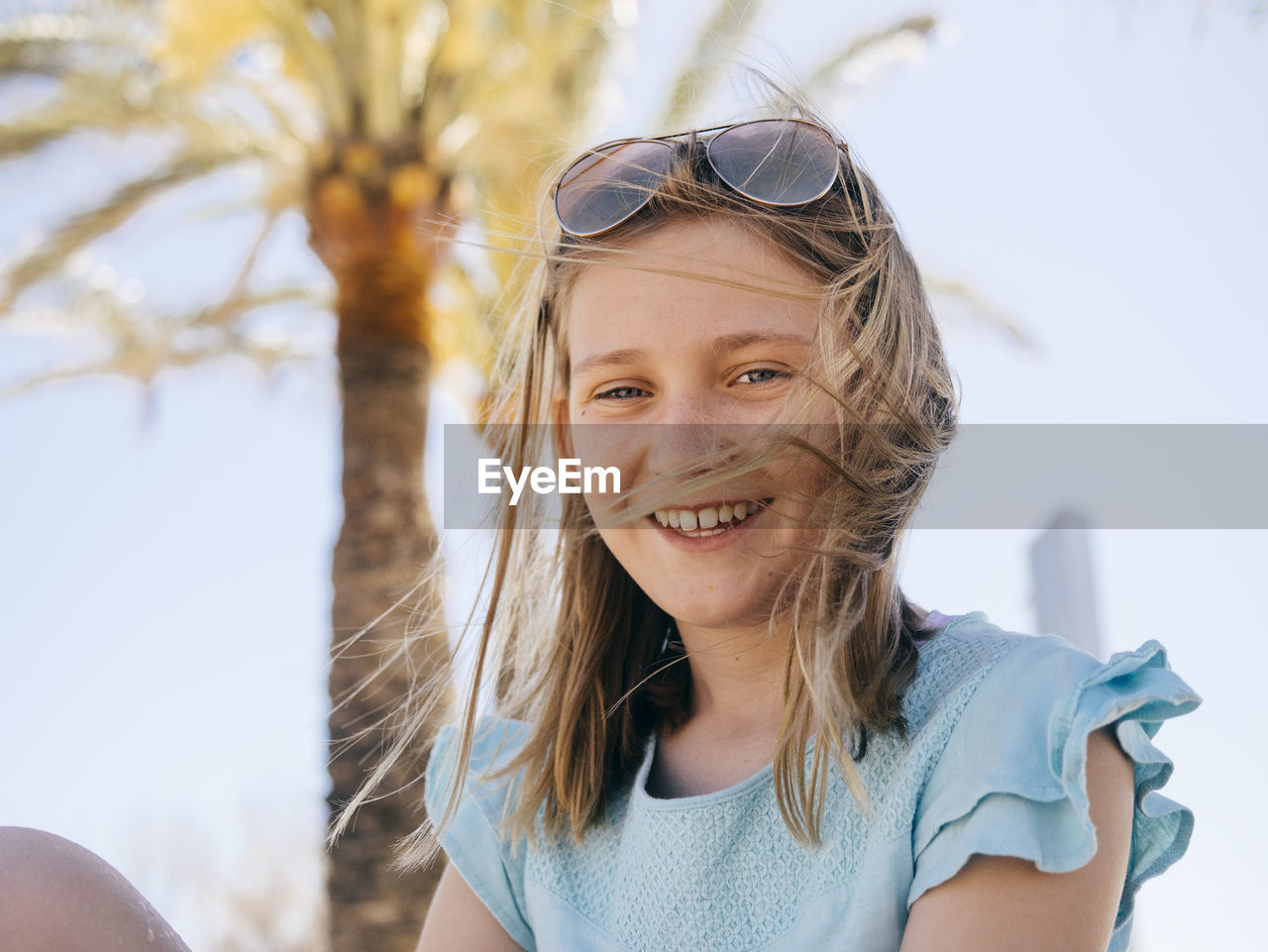 Portrait of smiling girl sitting against sky