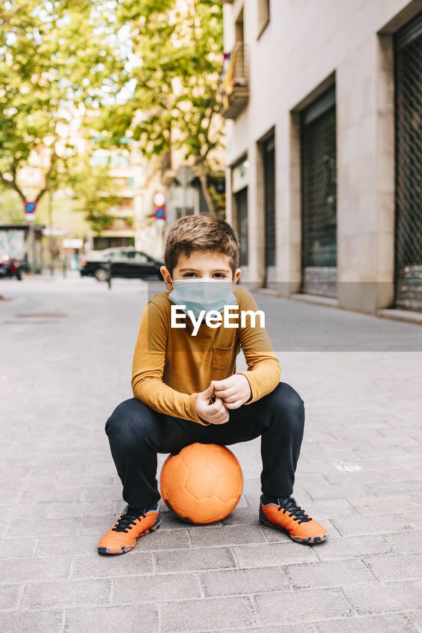 Little boy with a ball and protective mask. coronavirus concept.