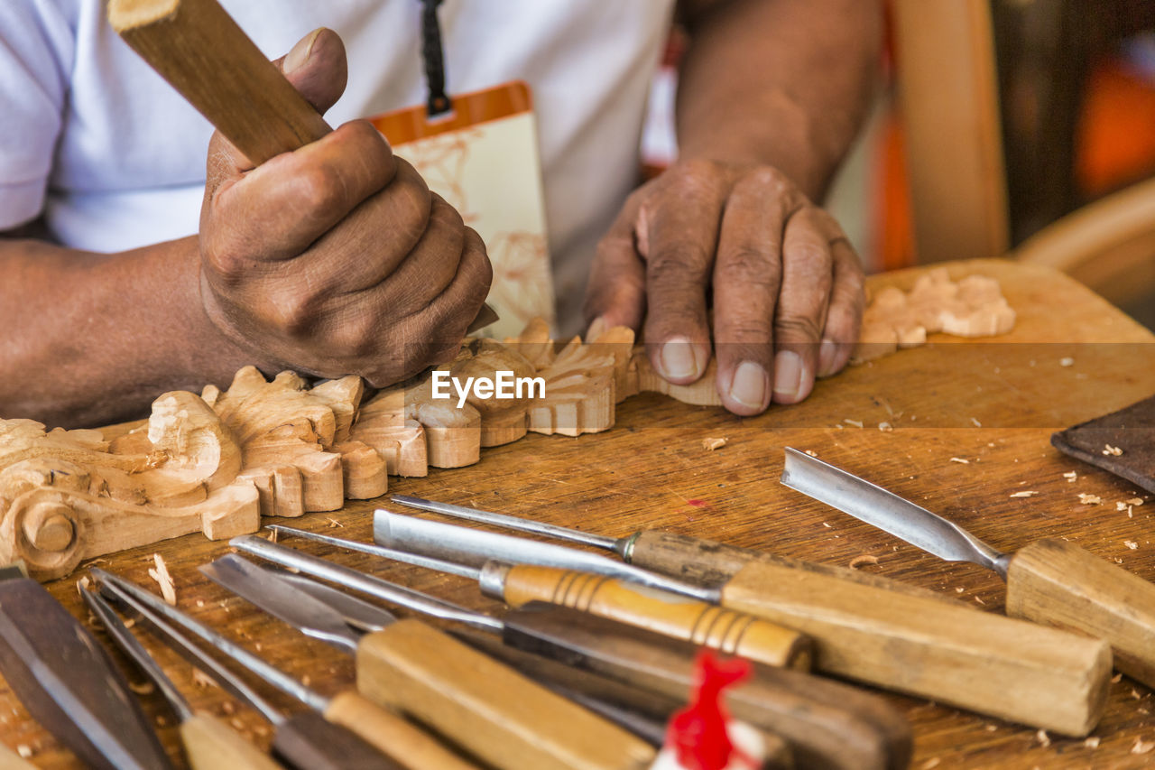 Midsection of man carving wood