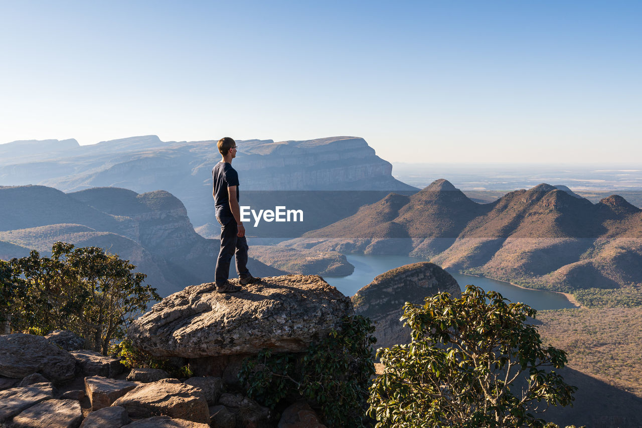 Man standing on mountain against clear blue sky