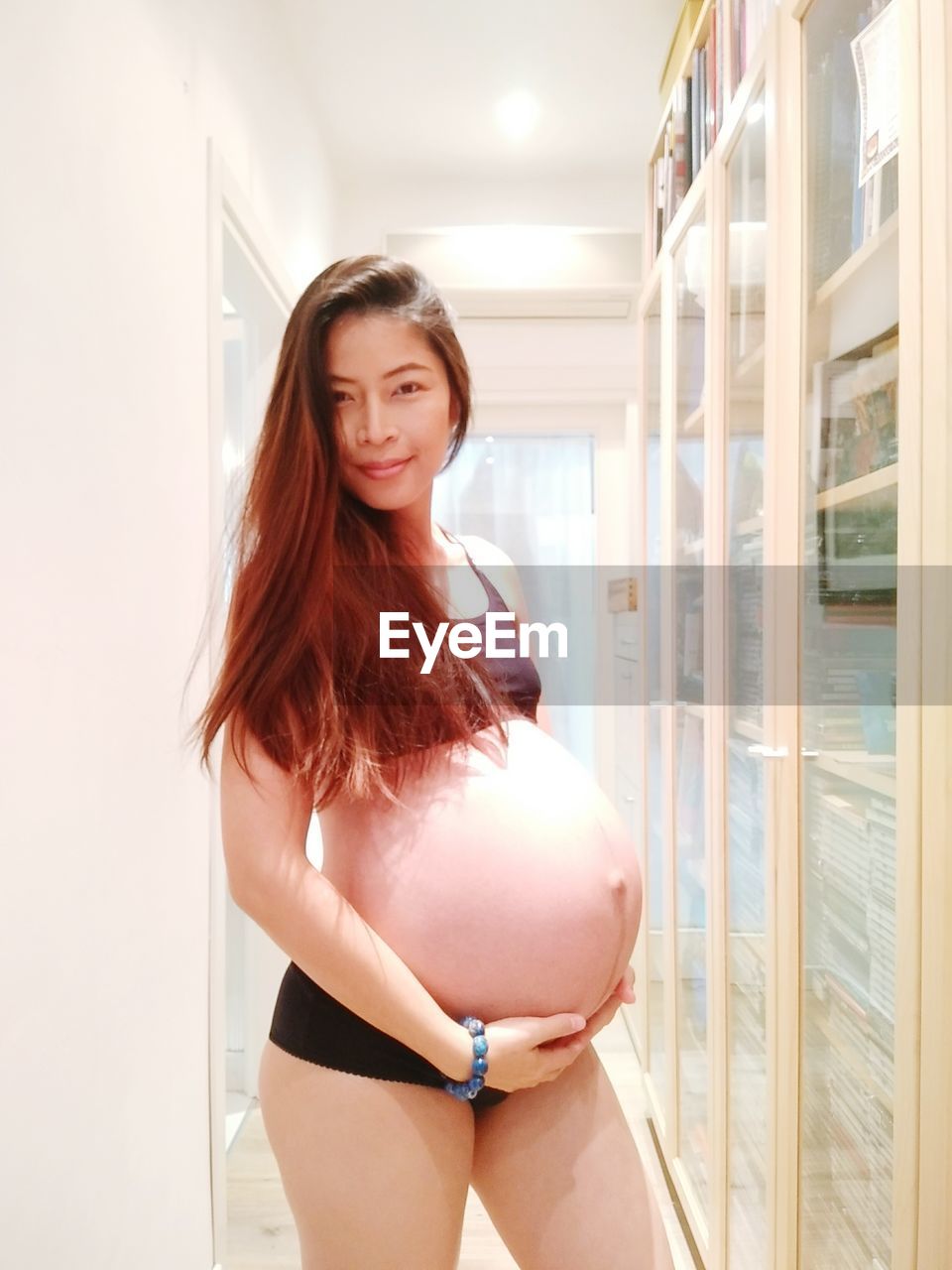 Beautiful pregnant woman standing in corridor at home