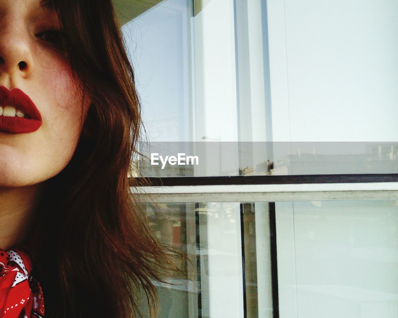 Close-up of young woman in red lipstick by window