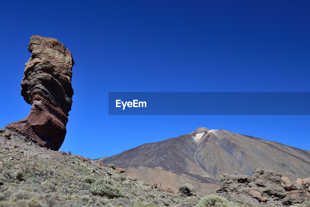 Scenic view of mountains against clear blue sky