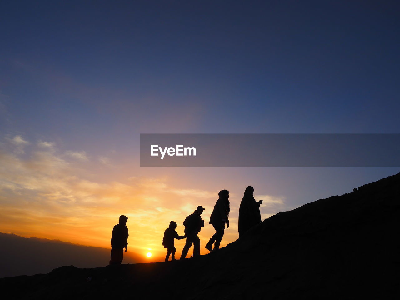 Silhouette people on mountain against sky during sunrise