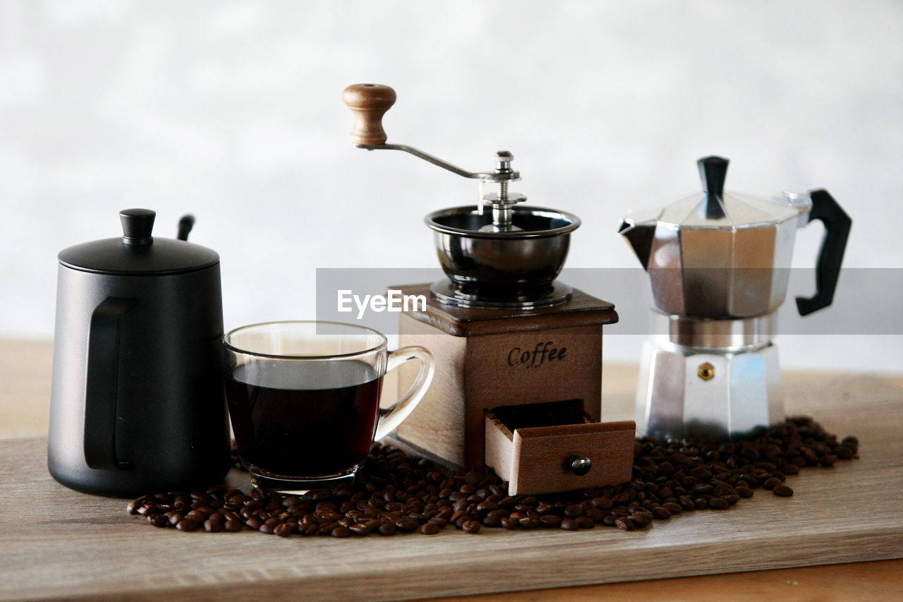 CLOSE-UP OF COFFEE CUP AND WINE ON TABLE