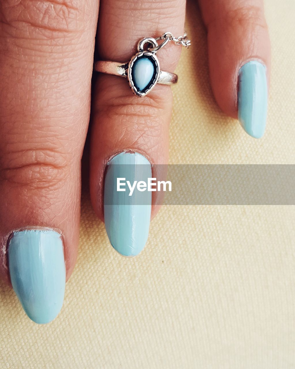 Cropped hand of woman with blue nail polish on table