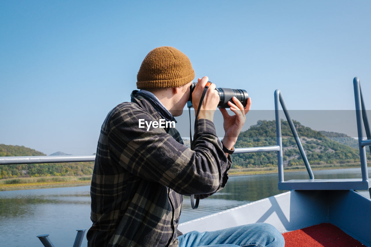 Rear view of man photographing against sky