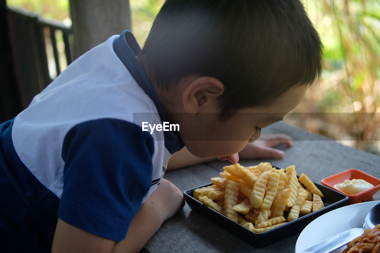 Close-up of boy licking food in plate on table