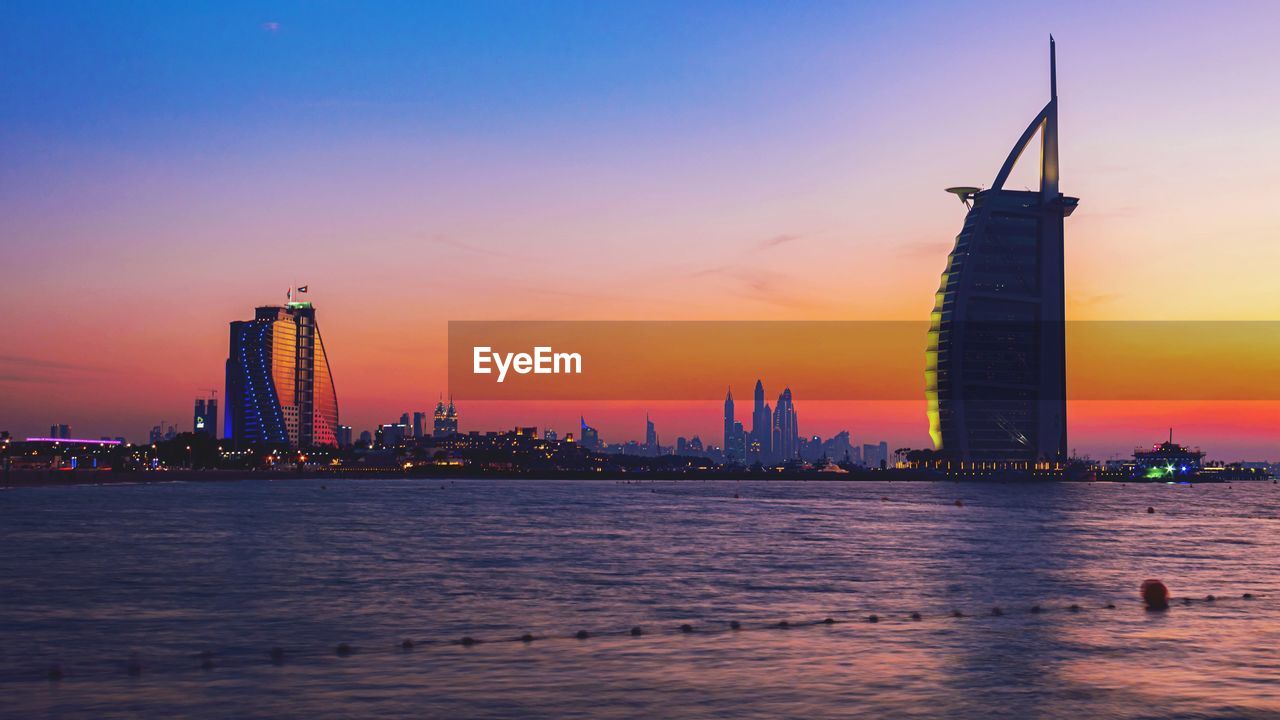 ILLUMINATED BUILDINGS IN CITY AT SUNSET