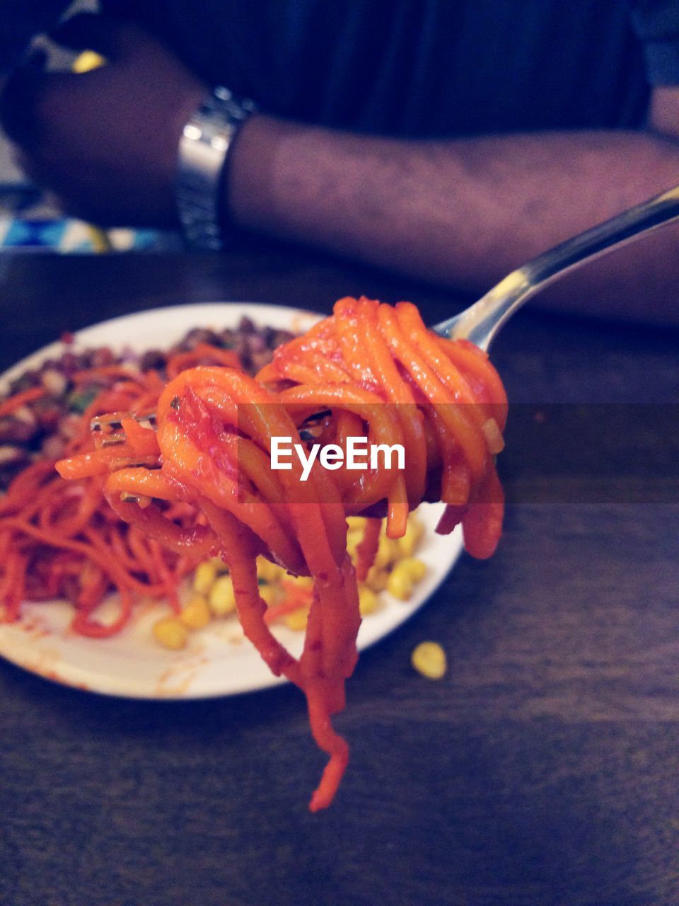 Close-up of fork with noodles at table