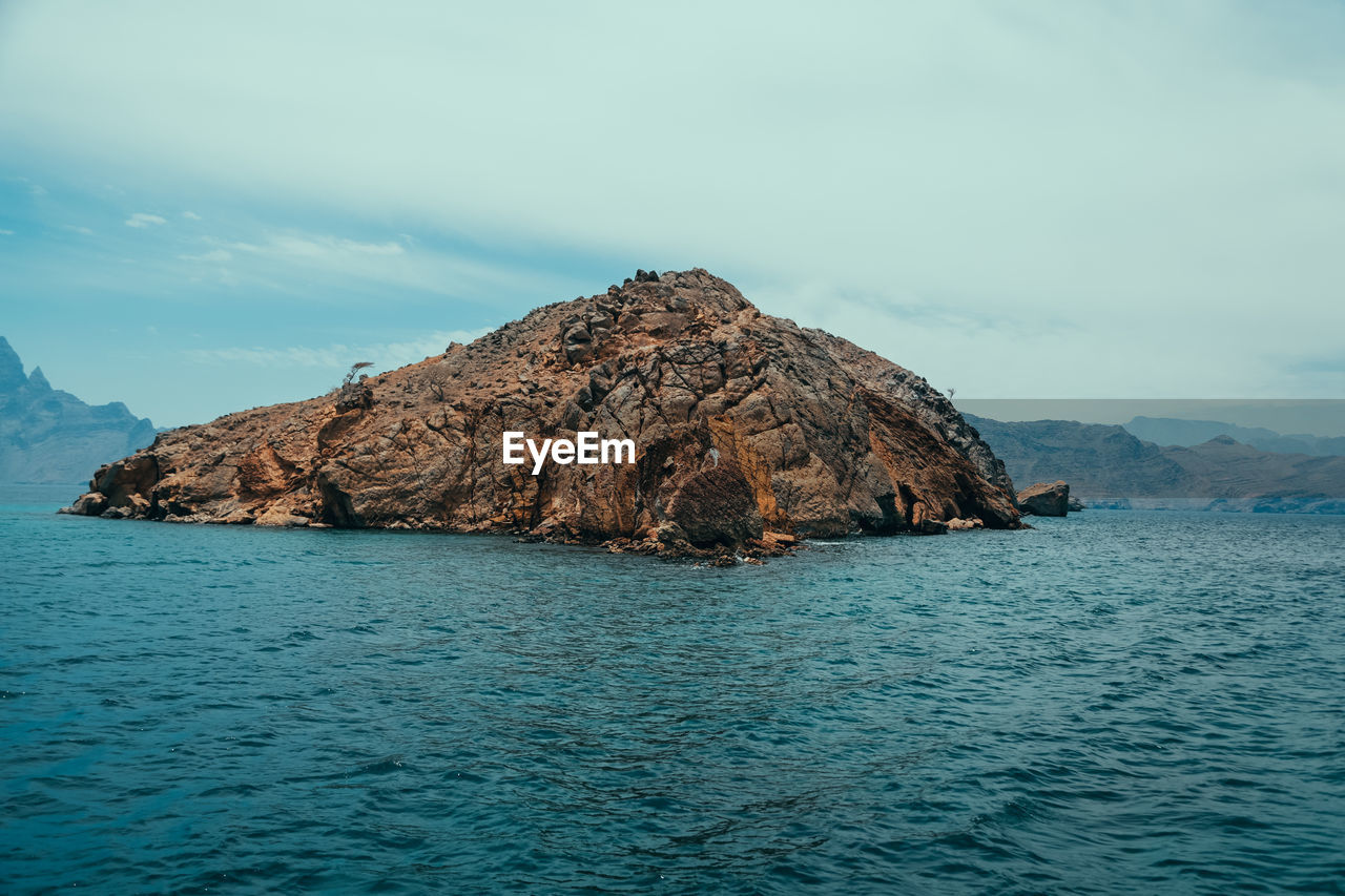 Rock formations by sea against sky