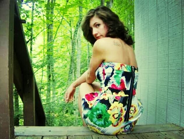 PORTRAIT OF YOUNG WOMAN SITTING ON WALL