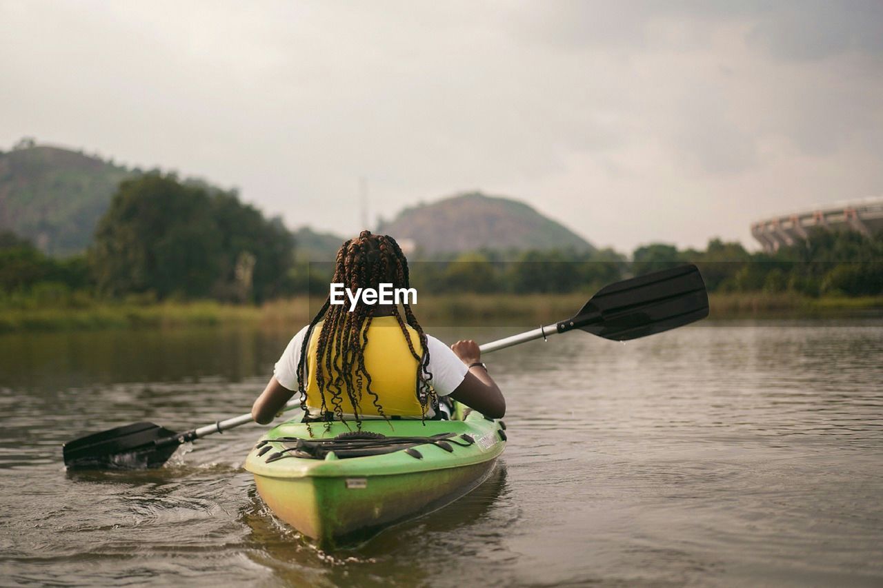 Rear view of man on boat in lake against sky