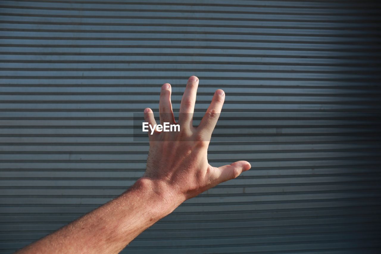Cropped image of hand against closed shutter