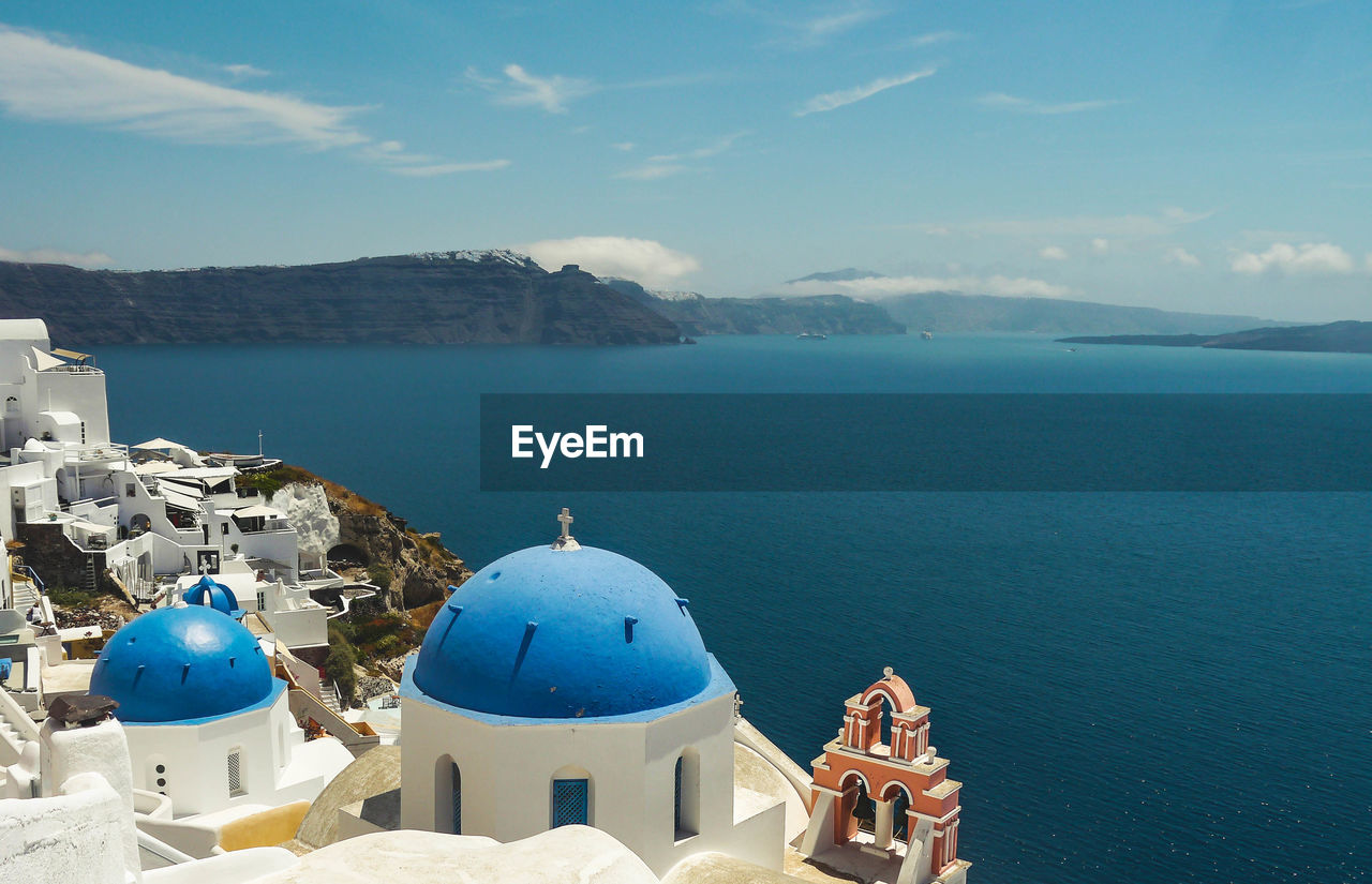 High angle view of sea against blue sky with greek blue church tower