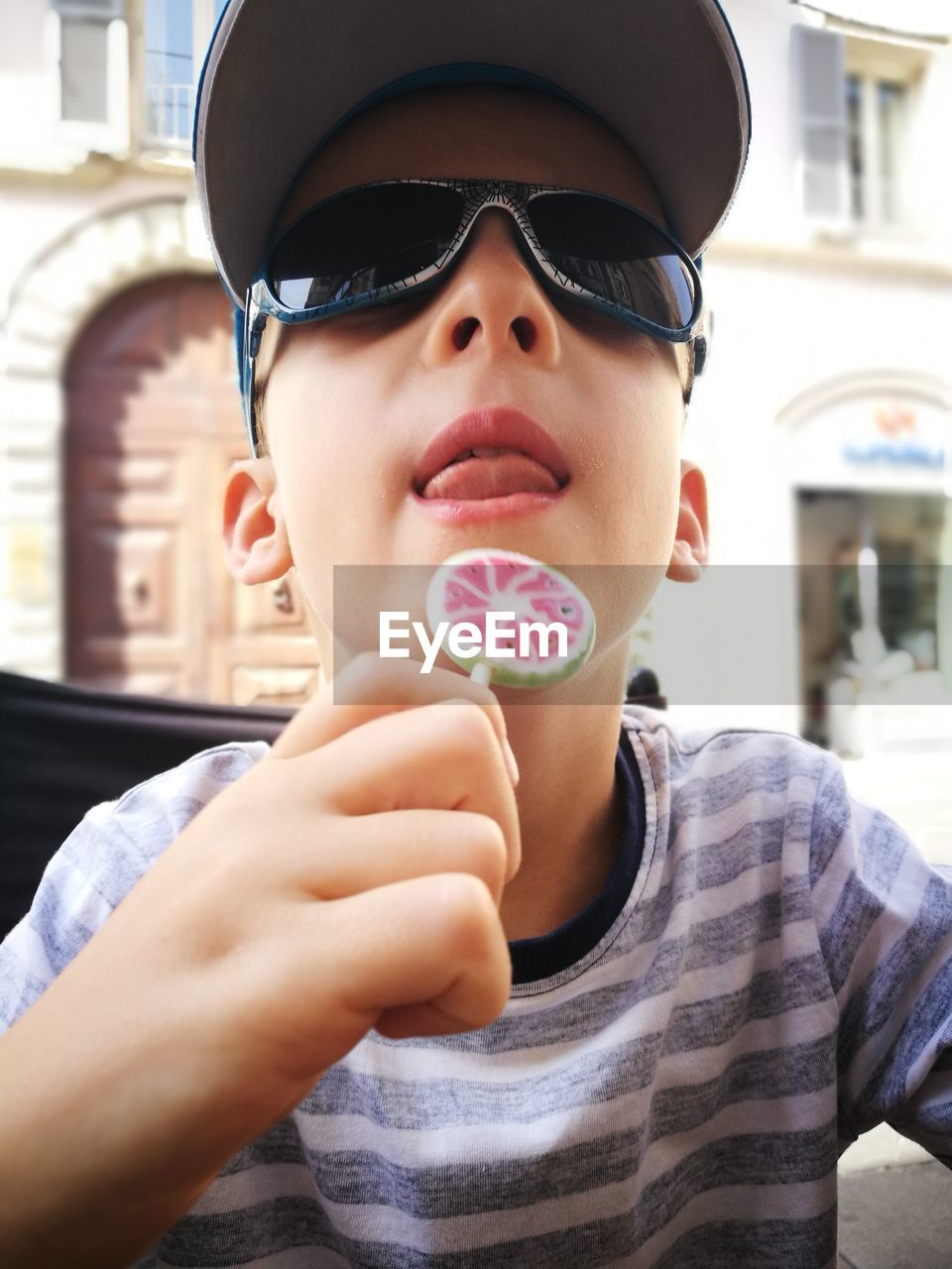 Low angle view of boy eating lollypop against building