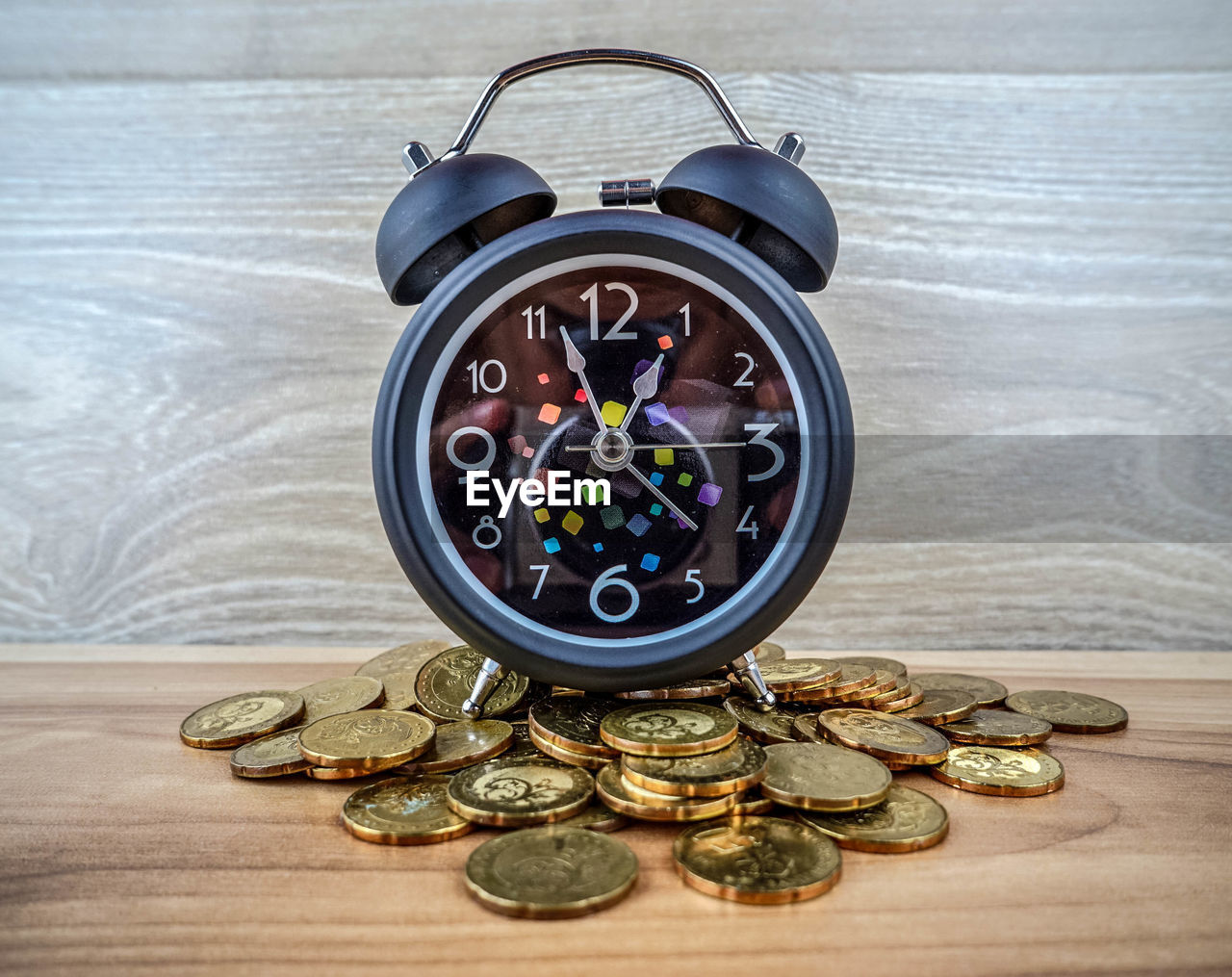 Close-up of coins and alarm clock on table