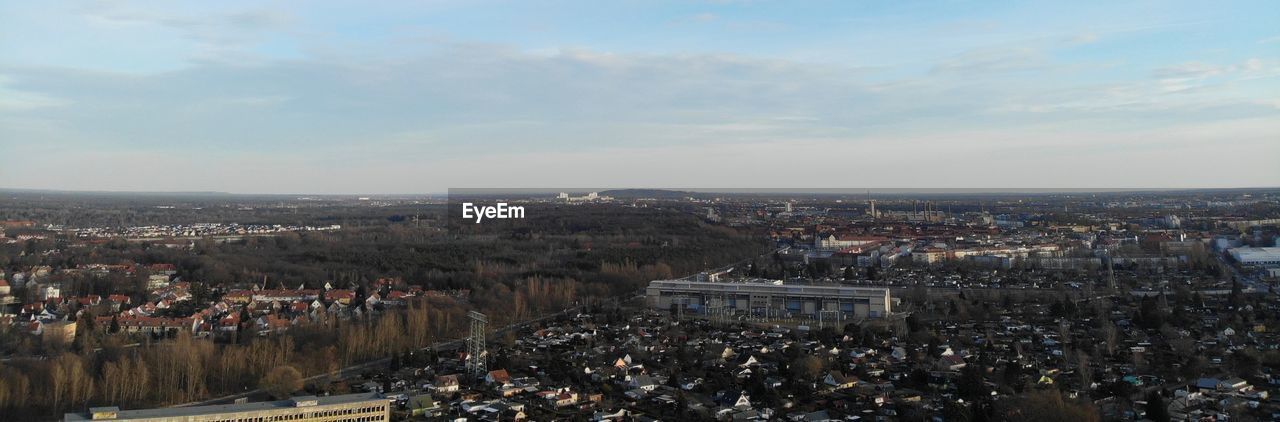HIGH ANGLE VIEW OF CROWD BY BUILDINGS AGAINST SKY