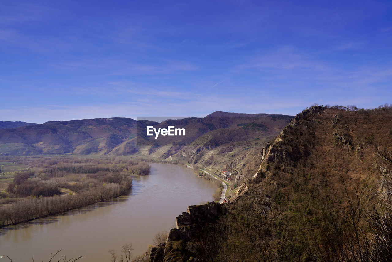 Scenic view of river and mountains against blue sky