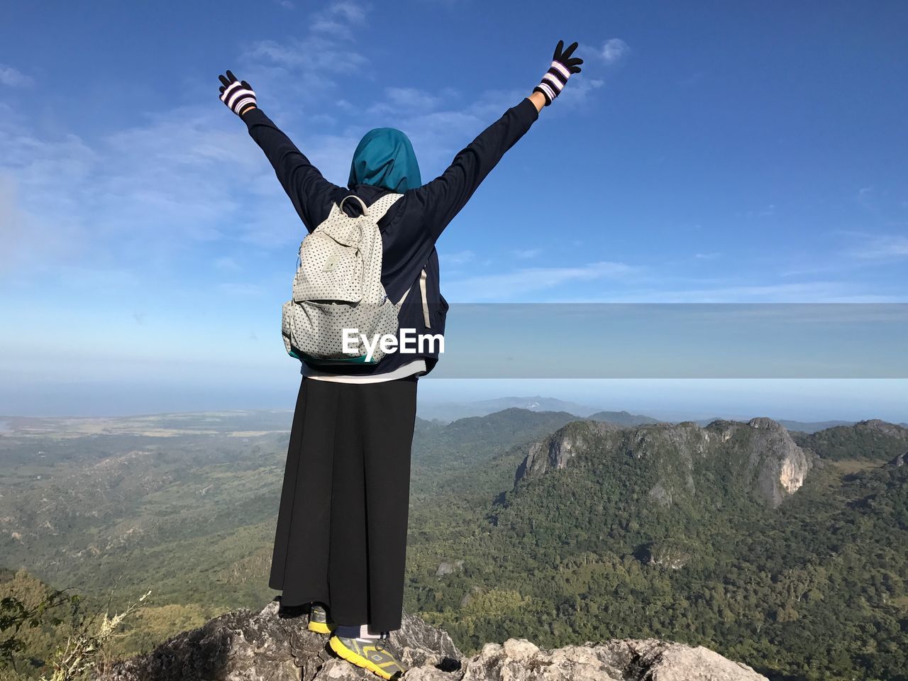 Rear view of woman standing on mountain against cloudy sky