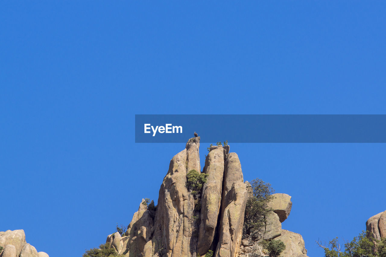 LOW ANGLE VIEW OF A ROCK FORMATION AGAINST CLEAR BLUE SKY
