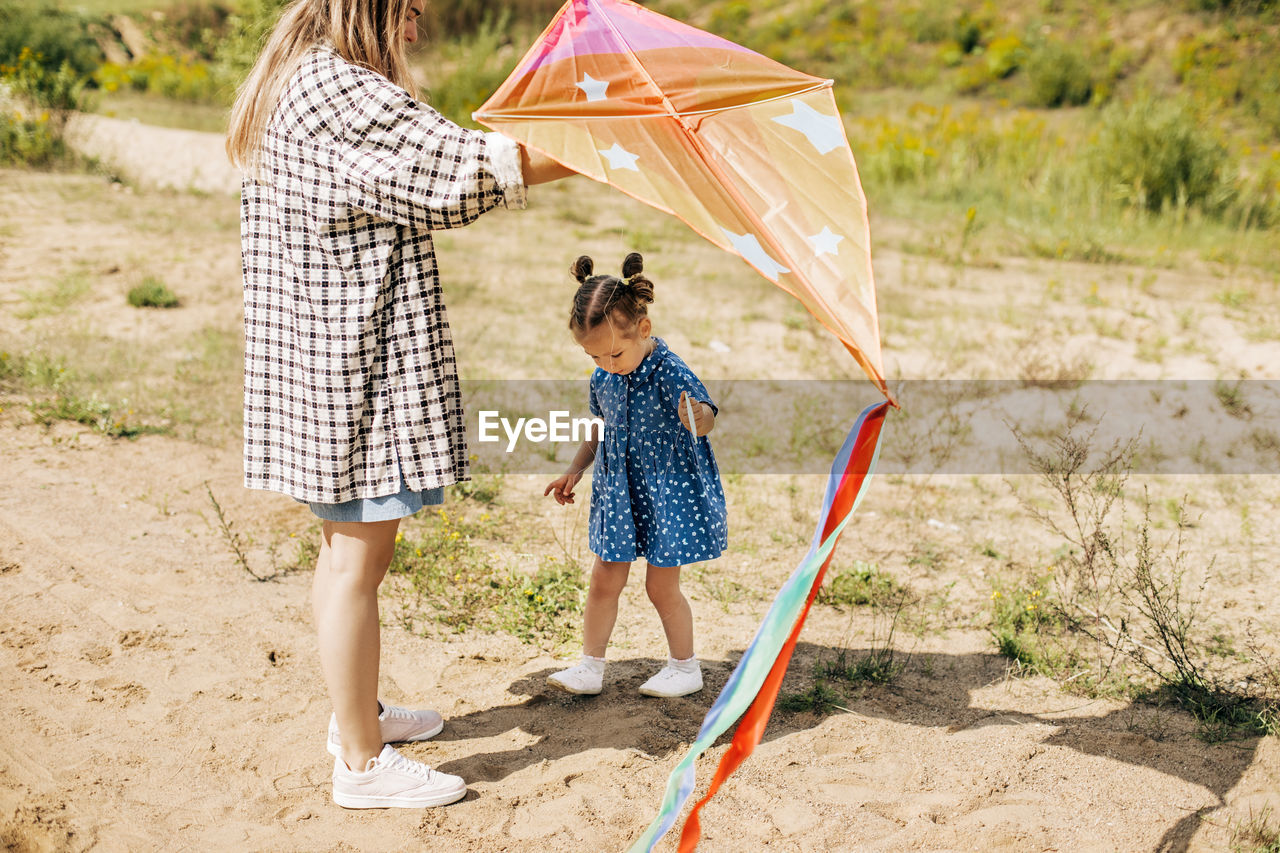 A charming little girl has fun and launches a kite together with her older sister