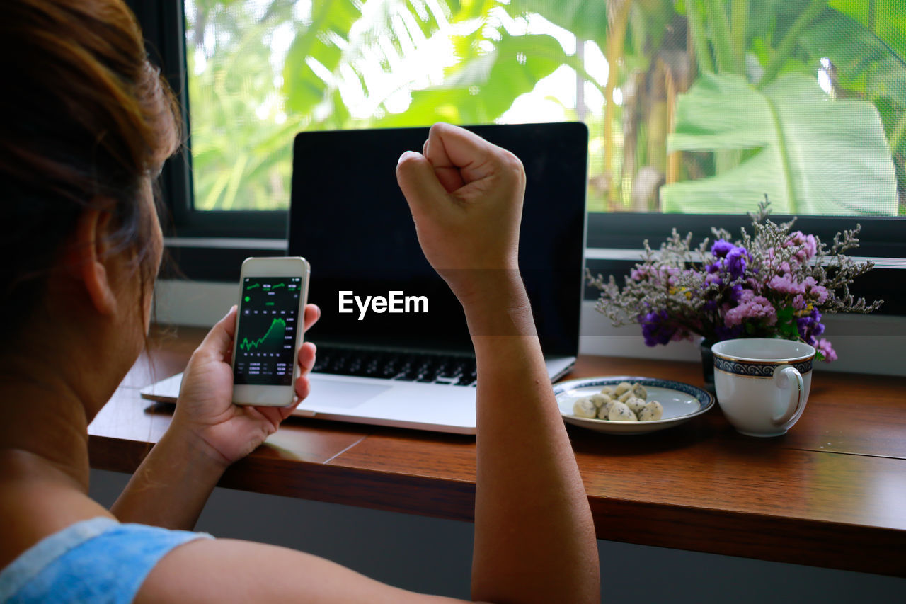 MIDSECTION OF WOMAN USING MOBILE PHONE IN RESTAURANT