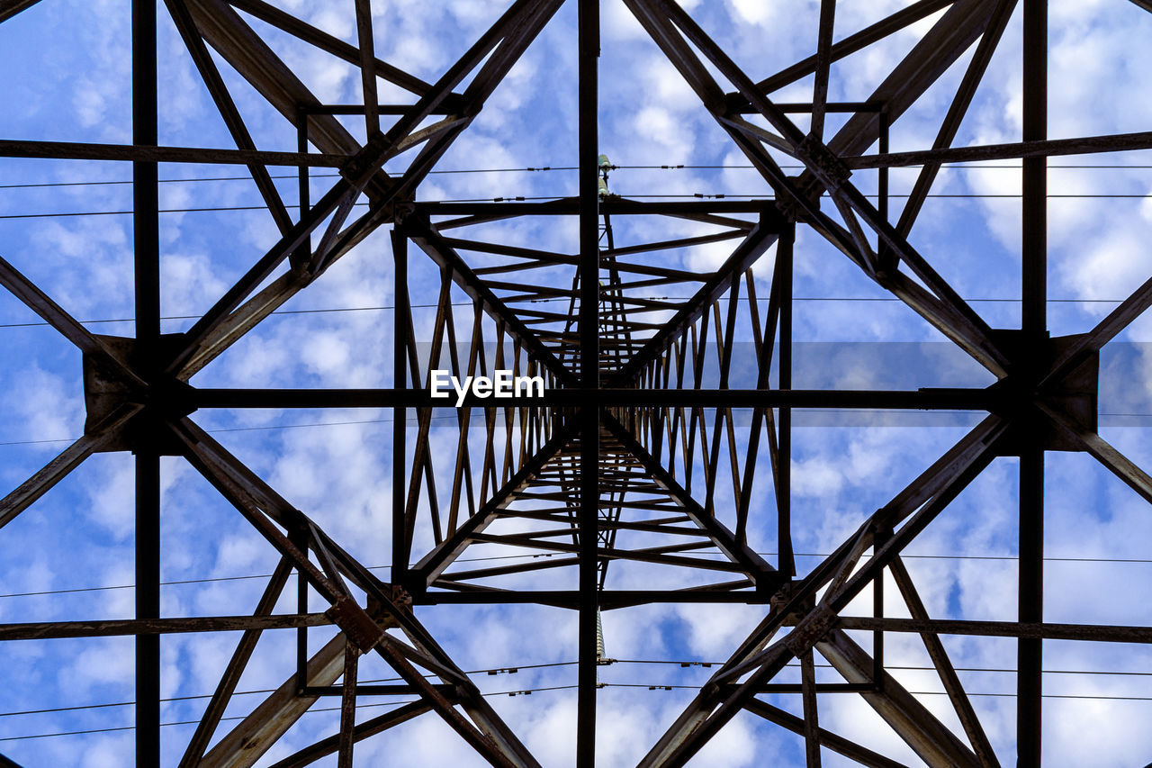 LOW ANGLE VIEW OF ELECTRICITY PYLON AGAINST SKY SEEN THROUGH METALLIC STRUCTURE
