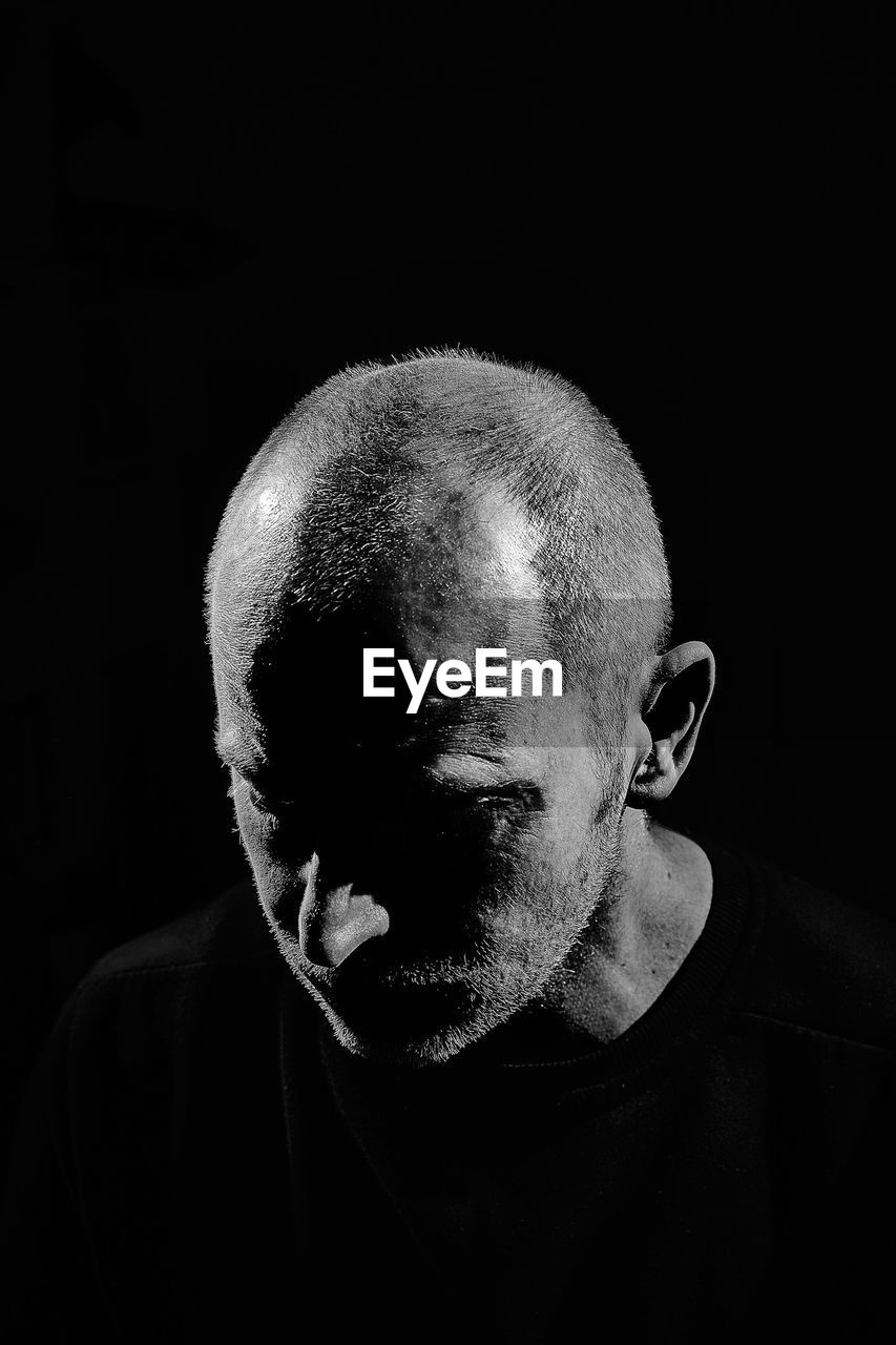Close-up of mature man against black background