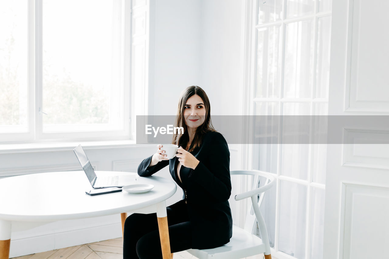 WOMAN SITTING ON TABLE AT HOME