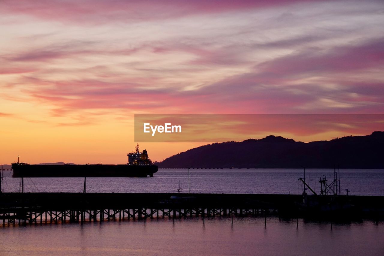 Silhouette pier over sea against sky during sunset