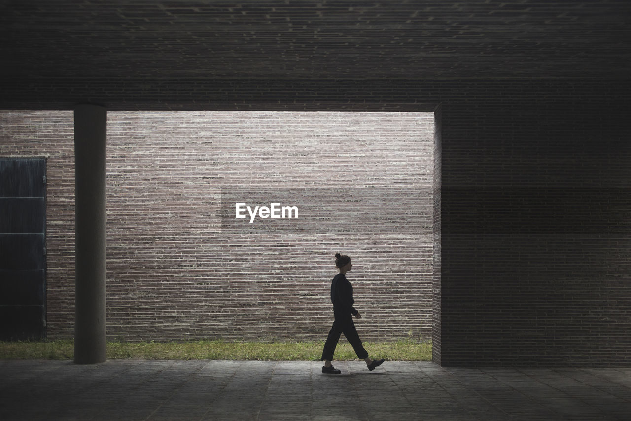 Side view of woman walking against wall