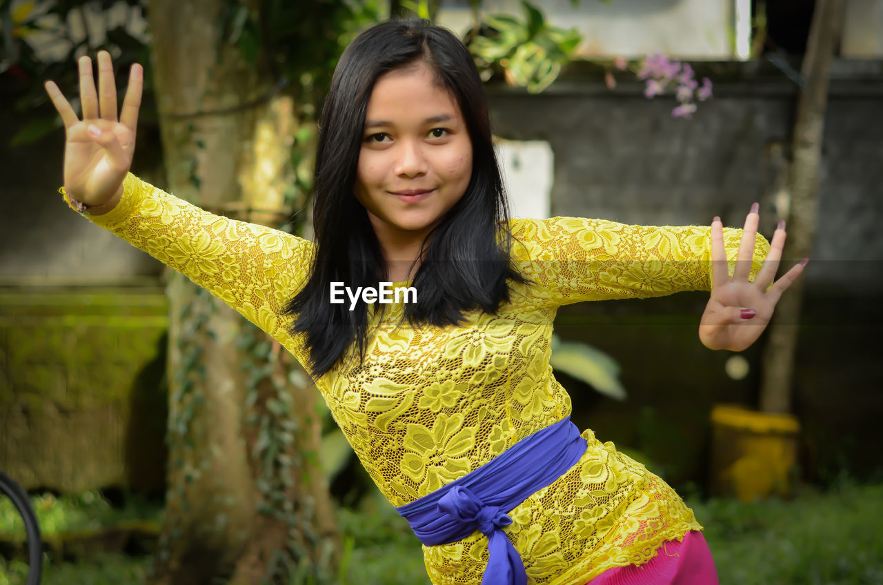 Portrait of young woman dancing while standing outdoors