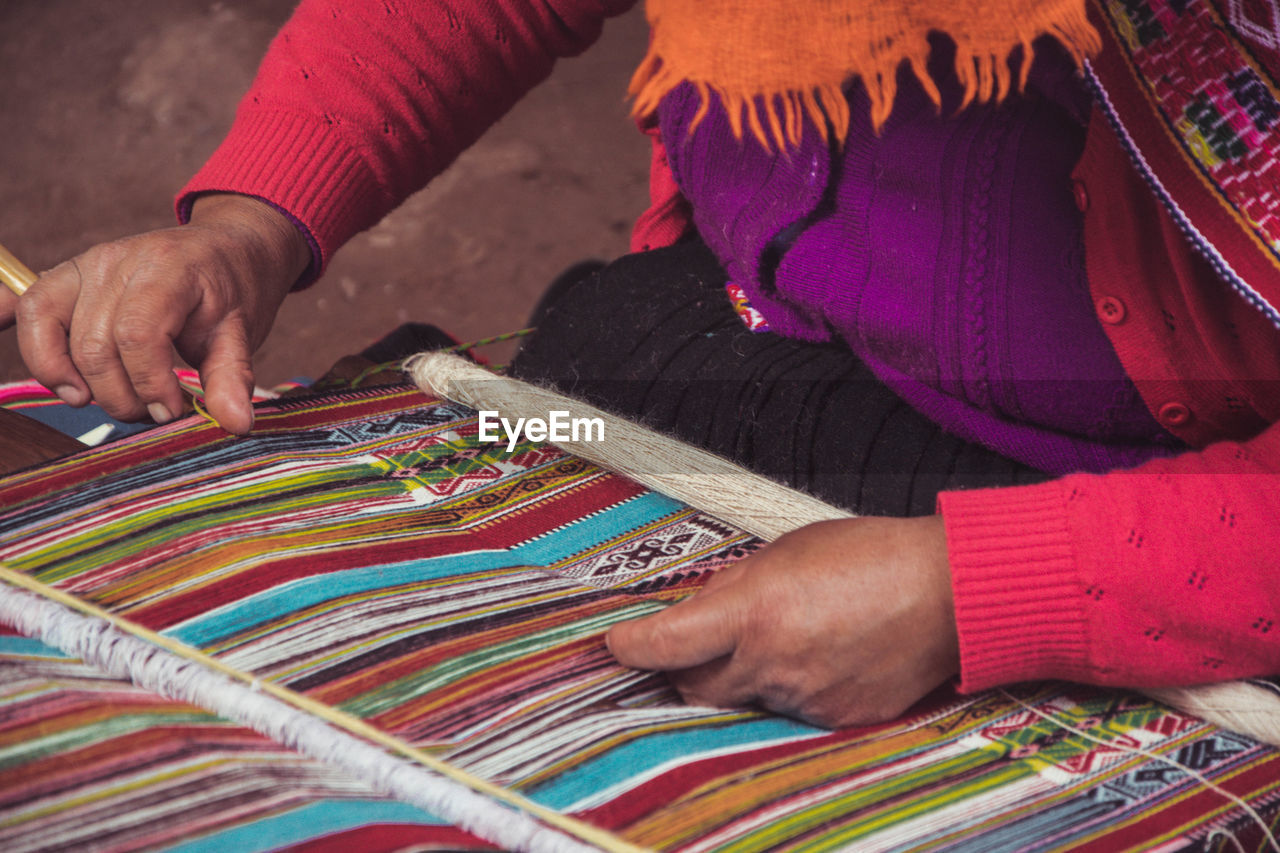 Midsection of man working on loom